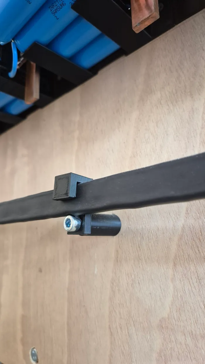 The 3D-printed clip that holds a busbar in place along the bottom row.