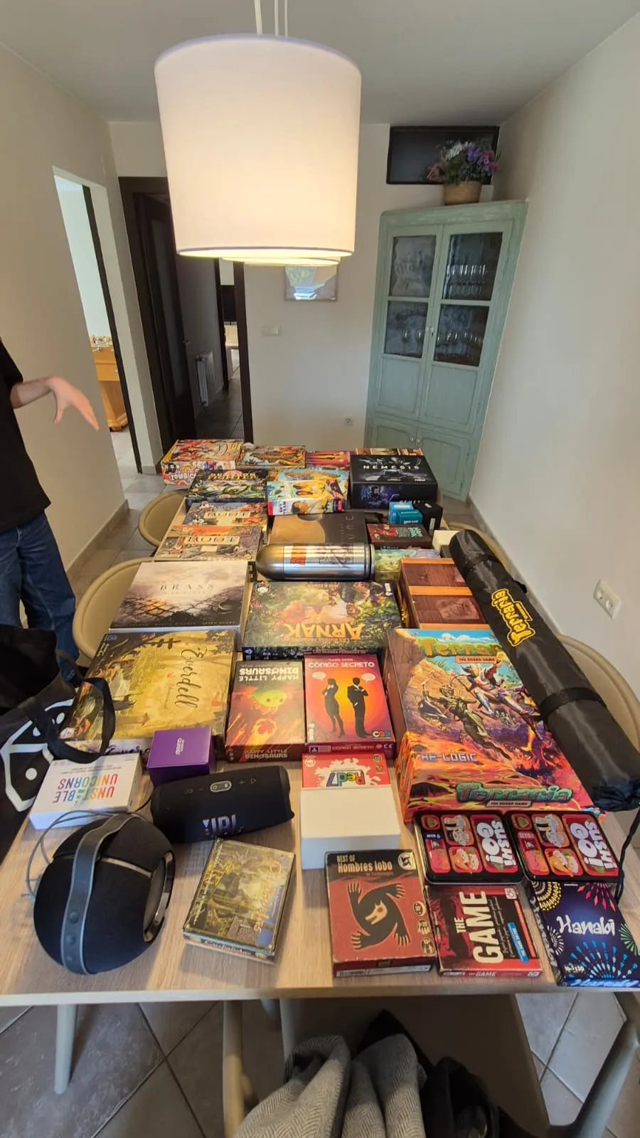 A table covered in board games ready for 3/4 days, including Brass, Arnak, Terraforming Mars, and Nemesis. Can you find one you've actually played? 🤔